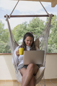 Midsection of woman using laptop while sitting outdoors
