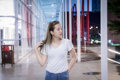 Beautiful young woman standing in illuminated building