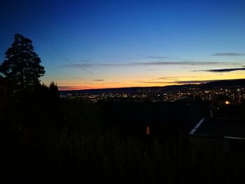 Silhouette of city against cloudy sky at dusk