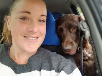 Portrait of smiling woman with dog in car