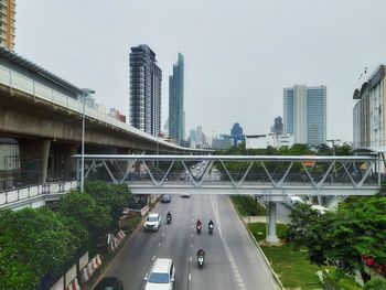 Bridge by buildings in city against sky