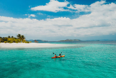 Man rowing boat in sea against sky