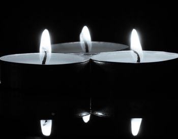 Close-up of burning candle against black background