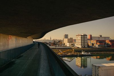 Bridge over river by buildings in city against sky