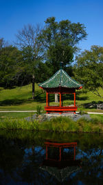 Built structure by lake against trees and sky