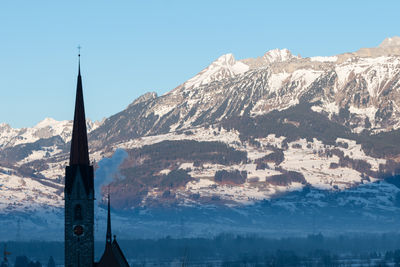 Schaan, liechtenstein, january 19, 2022 tower of the catholic church in front of the swiss alps 