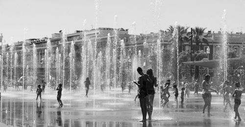 People on fountain against sky during rainy season