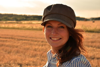 Portrait of young woman smiling while wearing cap on field