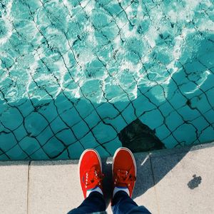 Low section of person standing by swimming pool