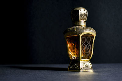 Close-up of glass bottle on table against black background