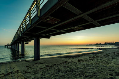 Pier over sea against sky during sunset