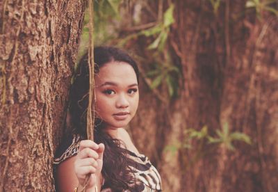 Portrait of teenage girl by tree trunk