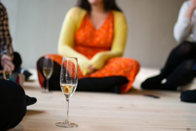 Champagne flutes by people sitting on floor