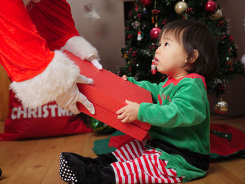 Santa claus giving present to baby girl at home