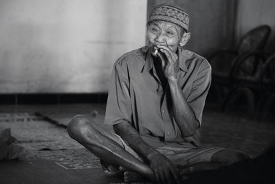 Man looking away while sitting on floor