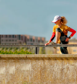 Woman standing by railing against wall