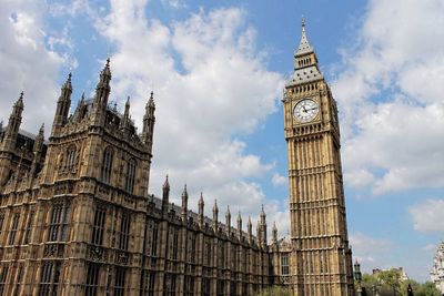 Low angle view of clock tower against cloudy sky