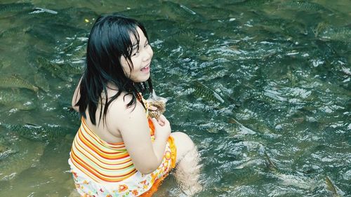 High angle view of smiling girl by fish in lake