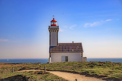 Lighthouse by sea against sky
