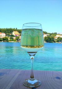 Close-up of drink on table by sea against clear blue sky