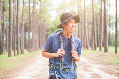 Man wearing hat while standing on land in forest