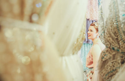 Close-up of young woman standing against dresses