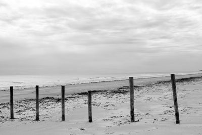 Wooden fence on beach against sky