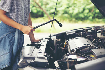 Midsection of mechanic repairing car outdoors