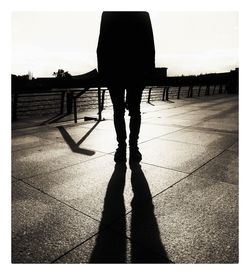 Rear view of silhouette woman standing on footpath