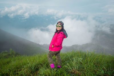 Portrait of mid adult woman wearing sunglasses standing on grassy field during foggy weather