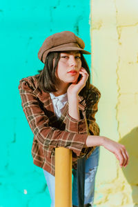 Full length of woman wearing hat against wall