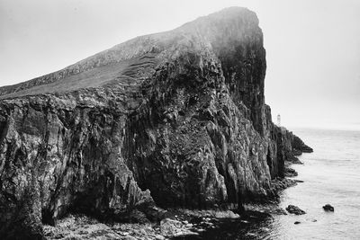 Rock formation in sea against clear sky