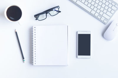 High angle view of office supplies with coffee on white background