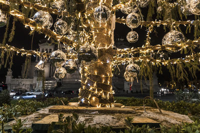 Statue by illuminated building against trees at night