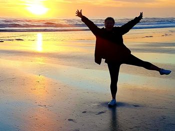Full length of man on beach against sky during sunset