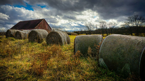 Farm landscape photo of a barn, hay bales, and a dramatic sky. 