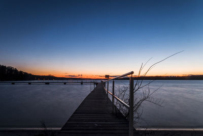 Pier over lake against clear sky during sunset