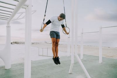 Full length of young woman exercising in playground