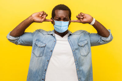 Full length portrait of young man standing against yellow background