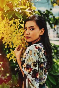 Beautiful young woman standing against plants