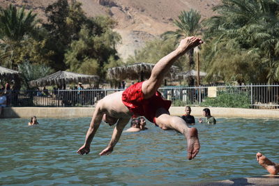Shirtless man diving into swimming pool at tourist resort