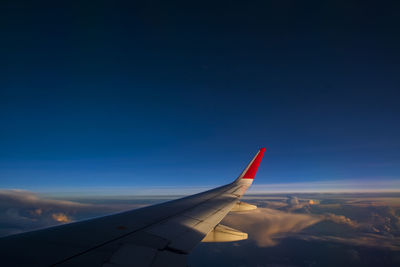 Low angle view of airplane wing against blue sky