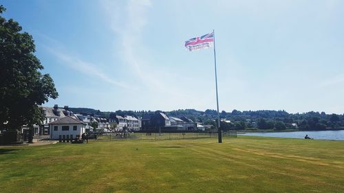 Flag on field by buildings against sky