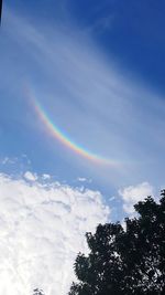 Low angle view of rainbow against blue sky