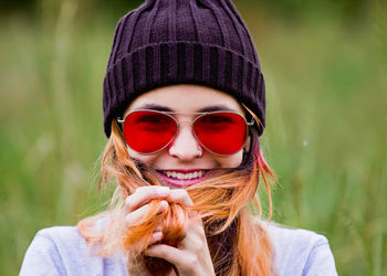 Portrait of happy young woman wearing sunglasses against plants