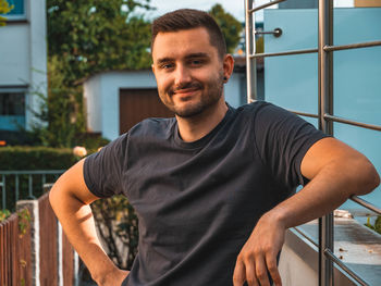 Portrait of young man standing against railing