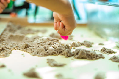 Cropped hands of child playing with sand