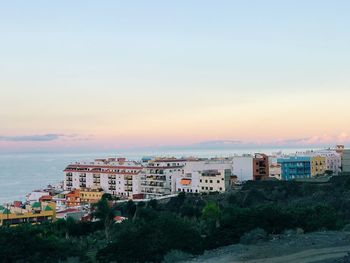 High angle view of buildings and sea against sky at sunset