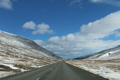 Road amidst snowcapped mountains against sky