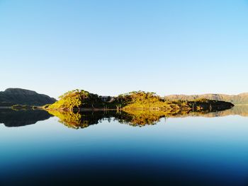 Scenic view of lake against clear blue sky